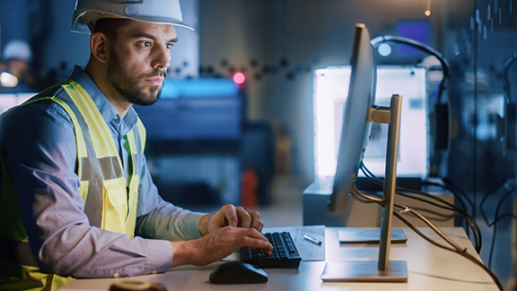 A maintenance engineer dressed in protective gear working on a monitor